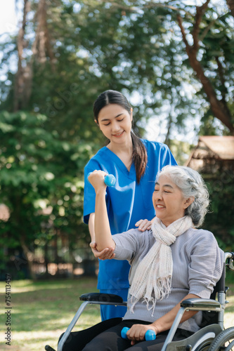 Asian physiotherapist helping elderly woman patient stretching arm during exercise correct with dumbbell in hand during training hand with patient Back problems in the garden.