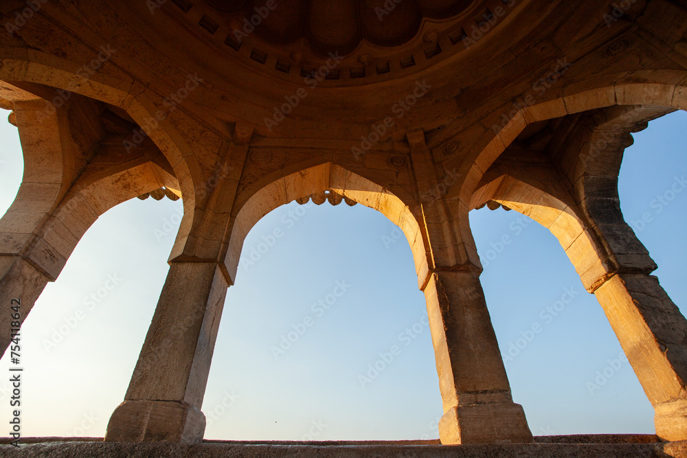 The arched doorway of a building with a view of the sunset, Mandu, India.