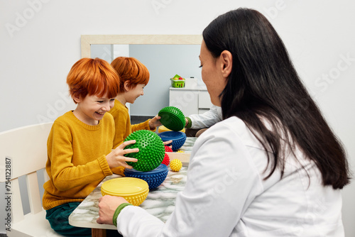 Male child with ASD working with sensory therapist using hedgehog half balls. Sensory integration therapy in pediatric rehabilitation