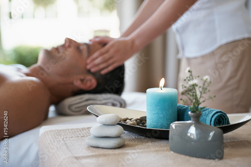 Luxury, facial massage and man relax in spa with aromatherapy candle for holistic treatment. Hotel, peace and health for male person, wellness and rest in resort for holiday for skincare in break