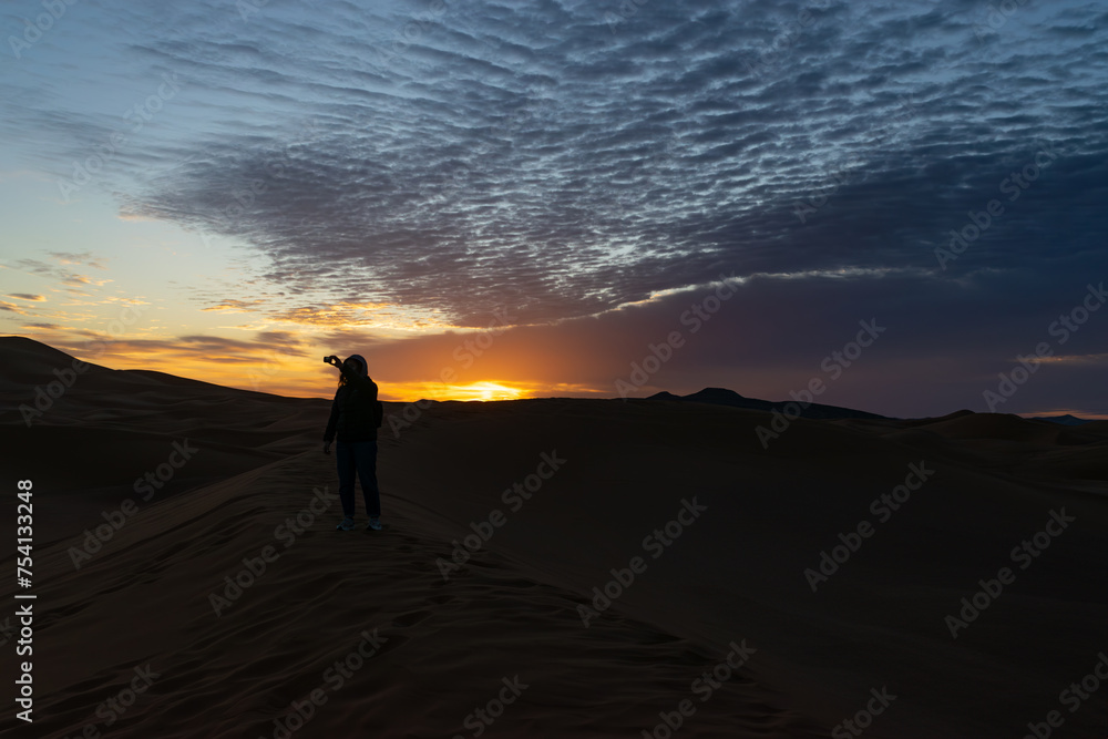 A Person taking a selfie at sunrise on a dune in the desert in Morocco