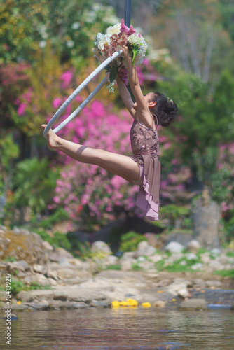 Beautiful Asian girl performing show aerial hoop or aerial ring in various positions and spinning stunts on the blue sky.
