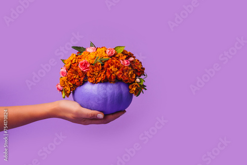 Happy Halloween Decorated Purple pumpkin decorated with orange flowers in hand