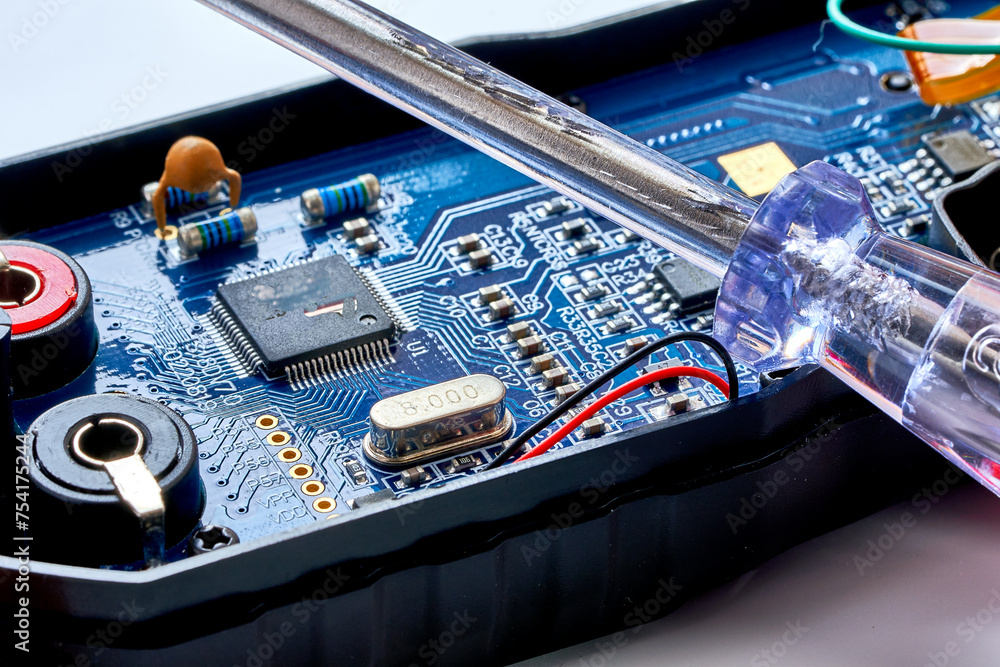 A screwdriver lies on a multimeter measuring device A screwdriver lies on a multimeter measuring device