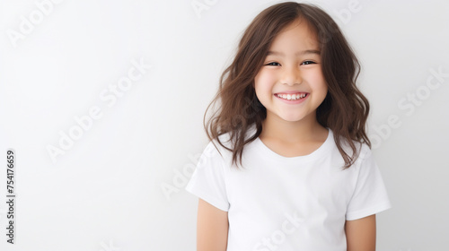 Smiling teenage girl in a white T-shirt on a white background mockup. Childhood lifestyle concept. Mockup copy space. Asian girl model
