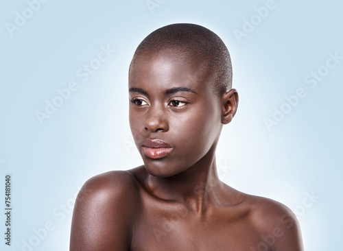 Face of black woman, natural skincare or thinking of beauty cosmetics or healthy skin in studio. Dermatology, wellness ideas or African girl model with glow or skincare results on blue background