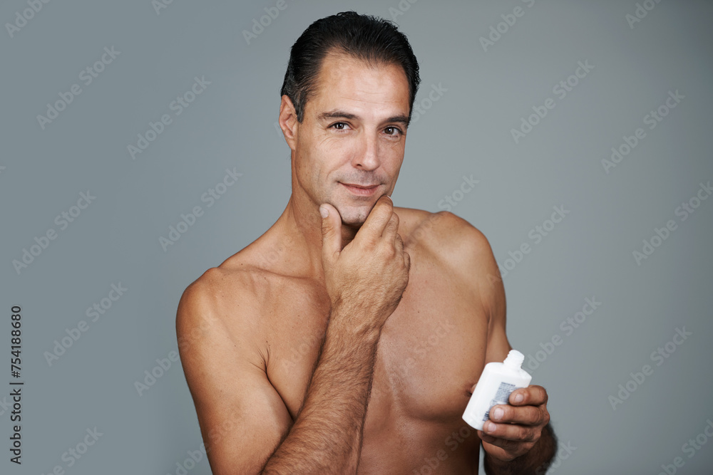 Man, portrait and moisturizer lotion in studio for skincare treatment for facial wellness, grey background or mockup space. Male person, product and healthy dermatology for anti aging, cream or apply