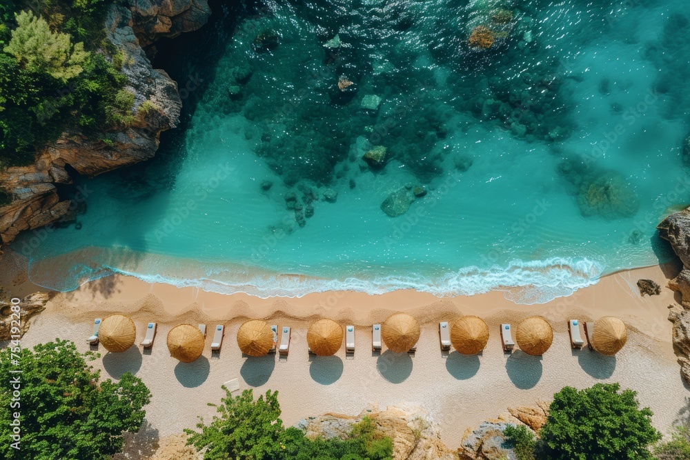 A perfect beach with blue water and golden sand. There are beautiful wooden umbrellas and sun loungers on the sand. view from above.