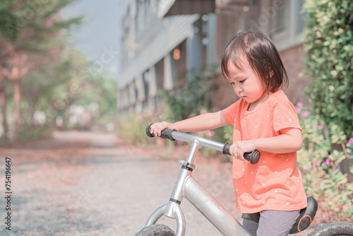 Little girl learns to keep balance while riding a bicycle at park. Copy Space.