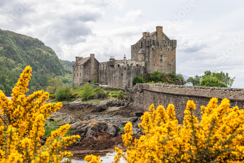Obraz na plátne Eilean Donan Castle stands against a dynamic Scottish landscape, with golden gor