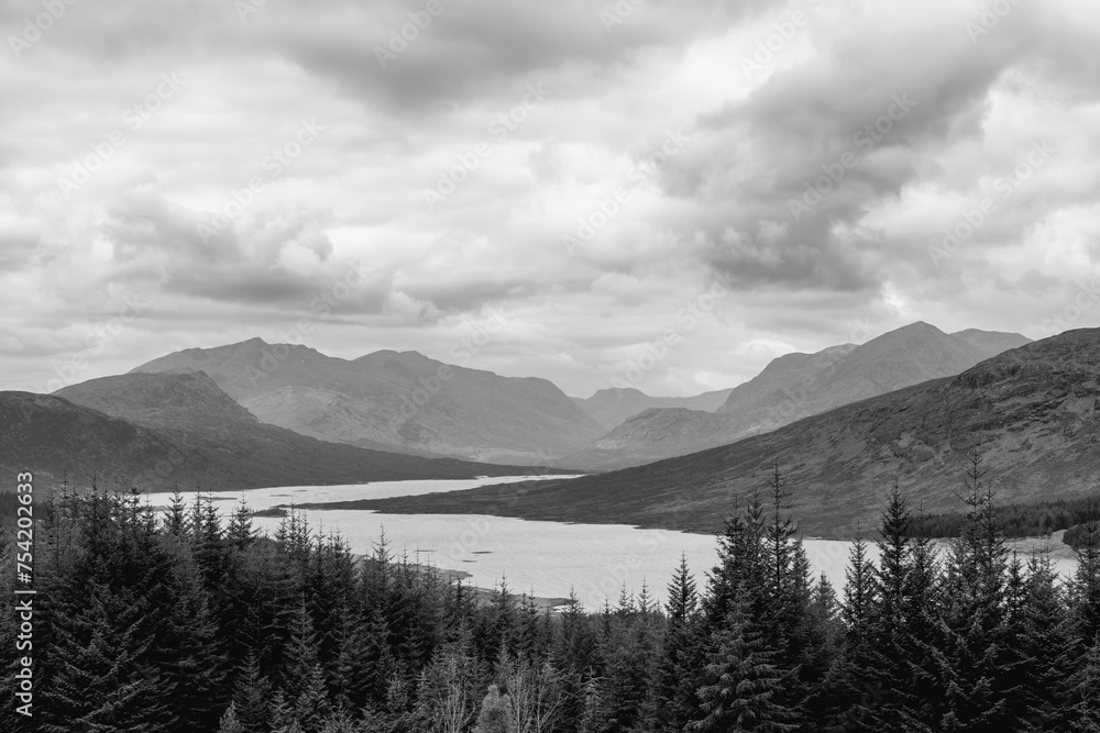 Overlooking Loch Loyne, this grayscale landscape showcases the rugged beauty of the Scottish Highlands, with layered mountain ranges under a textured sky
