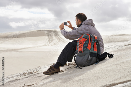 Phone, photography or man in a desert for travel, adventure or profile picture in nature. Smartphone, app and social media nomad influencer with photoshoot of sand dunes scenery on journey in Egypt photo