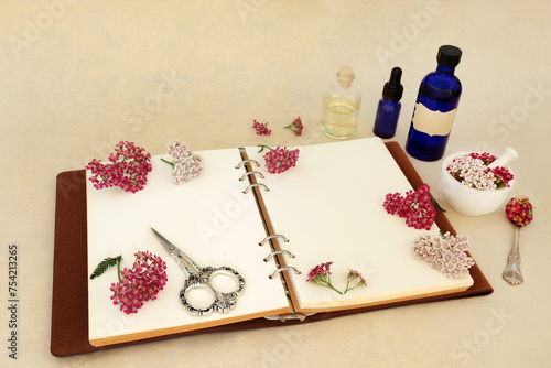 Achillea yarrow herb flower preparation. Natural  herbal medicine remedy with notebook, tincture and oil bottles and mortar. Treats hemorrhoids, wounds, bloating, flatulence. On hemp paper.