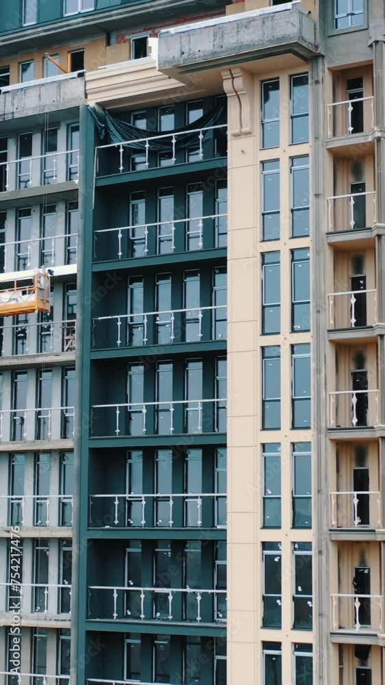 Construction of a modern building in the city. Facade of multistorey apartment house with plastic windows in the city. Building of a new architecture. Vertical video. Construction of a modern building in the city. Facade of multistorey apartment house with plastic windows in the city. Building of a new architecture. Vertical video.