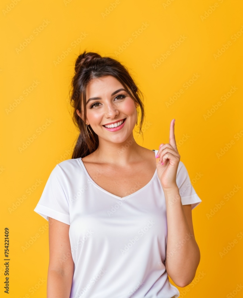 Upbeat woman points upward against a sunny yellow background Upbeat woman points upward against a sunny yellow background