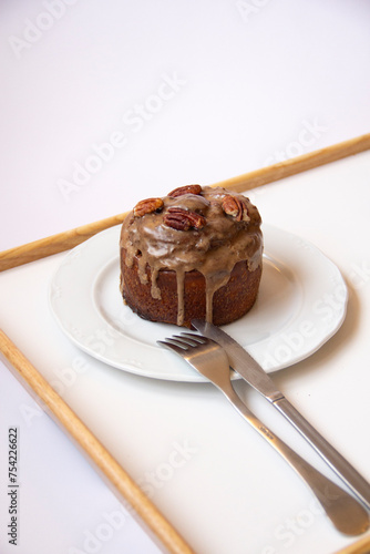 Rollito de canela con nueces pecanas enplatado y en bandeja sobre fondo blanco photo