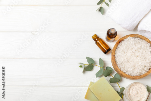 Beautiful spa composition on a wooden background with eucalyptus leaves. Beauty and fashion spa concept with body cream, scrub, mask, essential oil and sea salt.Cosmetic product. Copy space.