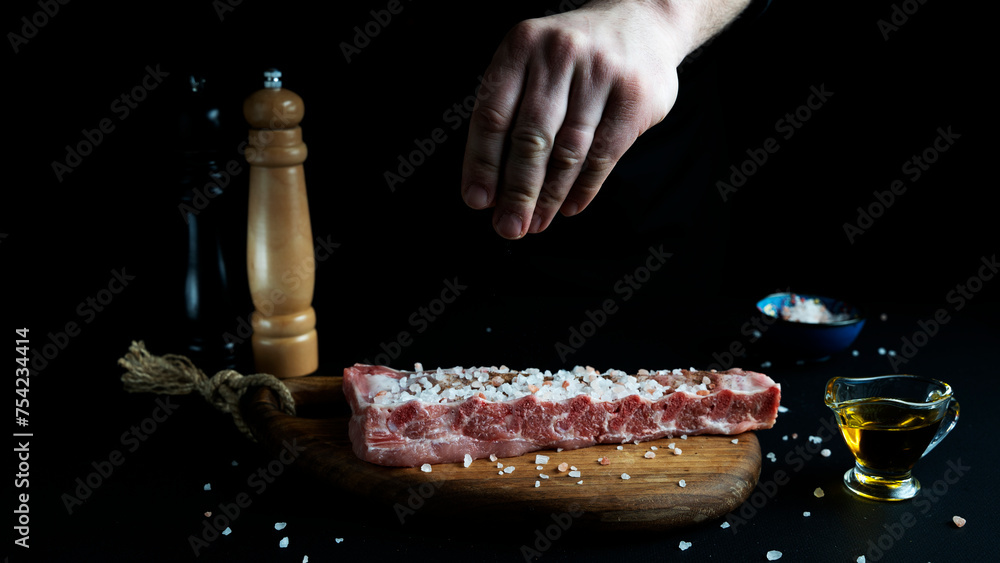 chef adding seasonings and spices to meat in