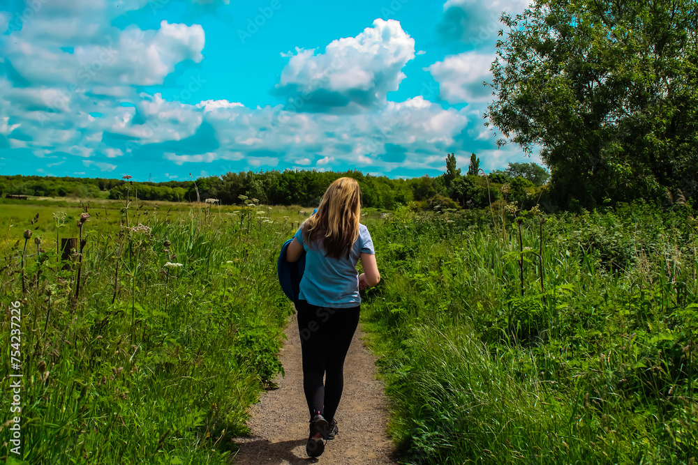A single woman walking through the countryside on a beautiful summer afternoon