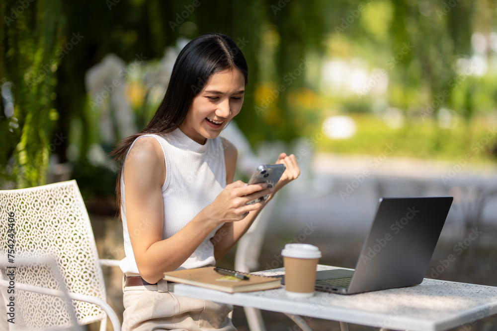 Young woman uses smartphone while working with laptop at outdoor cafe and coffee. Young woman uses smartphone while working with laptop at outdoor cafe and coffee.