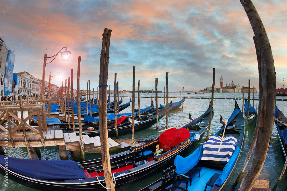 The spectacular sky reflects the beauty of Venice with the gondolas in the foreground, an illuminated street lamp adds a romantic touch to the scene.