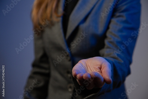 Part of a business woman with her arm extended forward and palm up close-up. Gray background. Blue color correction