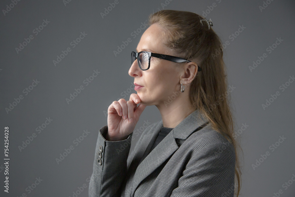 Close-up portrait of a business woman in glasses who is thinking. Gray background Close-up portrait of a business woman in glasses who is thinking. Gray background