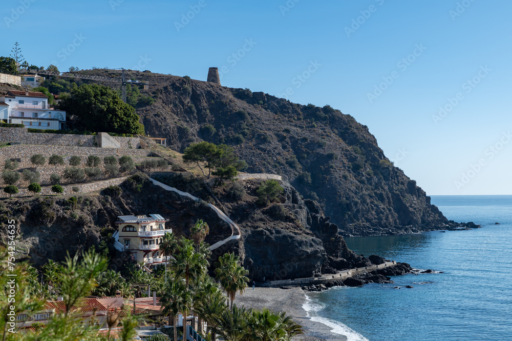 View of the beautiful Cabria beach in Almuñécar (Spain) on a sunny winter morning with the Torre de los Diablos over the mountain