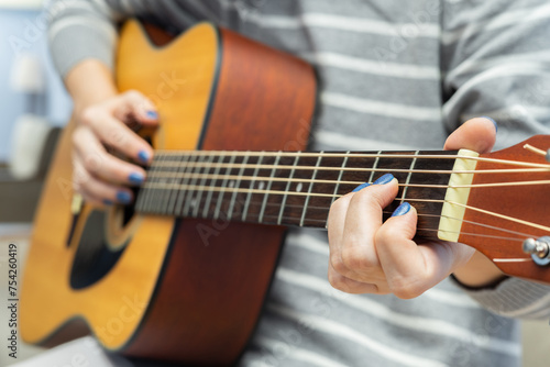 girl playing acoustic guitar at home, closeup