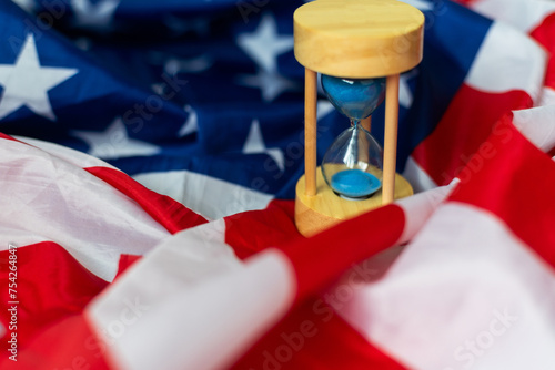 Hourglass and USA flag, soft focus, copy space photo