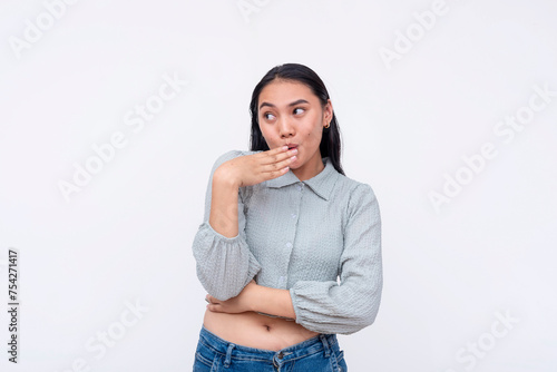 Surprised young Asian woman with hand over mouth, reacting to shocking and salacious gossip. Isolated on a white background. photo