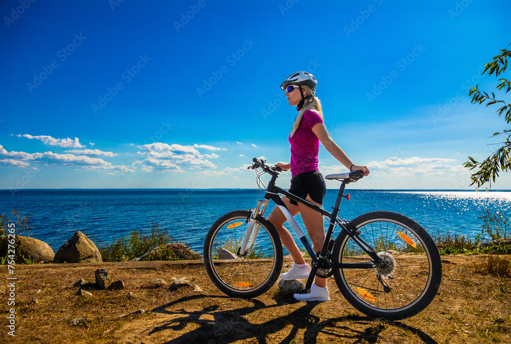 Fototapeta premium Beautiful young woman riding bicycle at seaside 