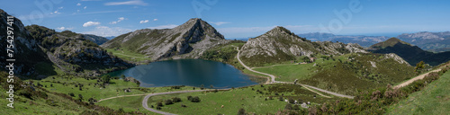Lagoons of Covadonga in peaks of europe with mountains, free wild cows and people in tourism attraction, during sunny summer day in spain