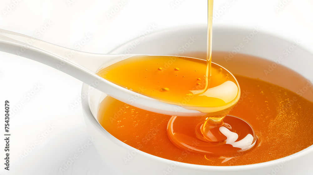 Honey pouring from a spoon into a bowl on a white background Honey pouring from a spoon into a bowl on a white background