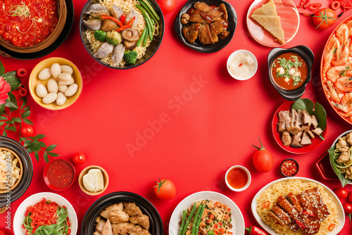 Chinese New Year festival table set over a red background featuring traditional Lunar New Year food. Flat lay, top view.