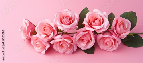A cluster of delicate pink roses in an artificial bouquet arranged neatly against a soft pink background. The vibrant pink hues of the flowers contrast beautifully with the matching backdrop.