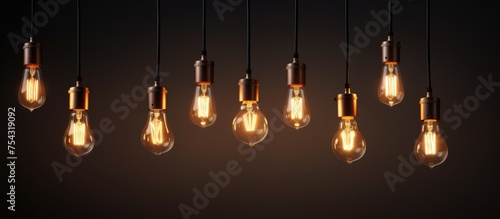 A collection of modern light bulbs hang from the ceiling, casting a warm glow in a dark room. The minimalist chandelier adds illumination and style to the space.
