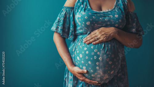 Pregnant woman cradling her belly, dressed in a floral dress.