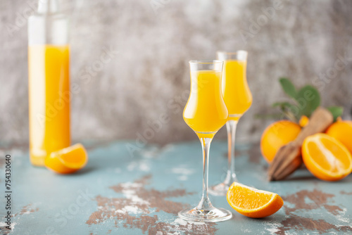 Принти на полотні Arancello in grappas wineglass, sweet Italian orange liqueur, traditional strong alcoholic drink and oranges on the light blue wooden background