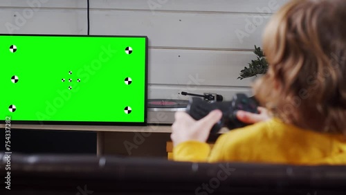 Kid playing console video game using tv with chroma key green screen