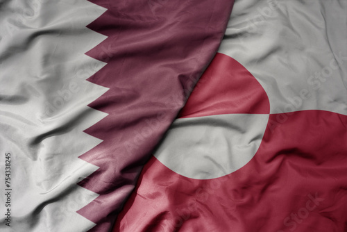 Fototapeta Naklejka Na Ścianę i Meble -  big waving national colorful flag of greenland and national flag of qatar.