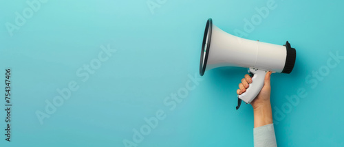 Hand holding a megaphone against a vivid blue background, symbolizing voice and announcement.