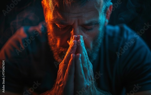 A multiracial man stands with his hands clasped in prayer