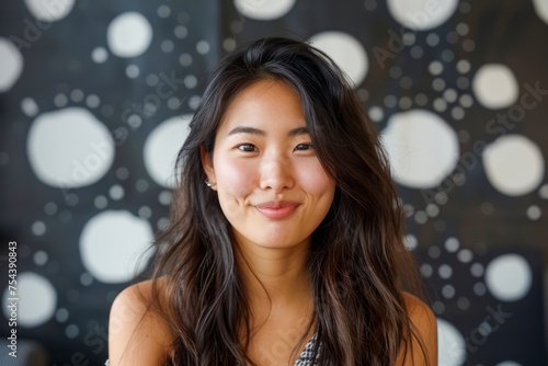 Portrait of a Smiling Young Asian Woman with Long Hair and a Modern Polka Dot Background © pisan