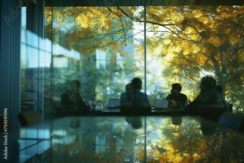 Diverse group of people having a meeting at a table in front of a window with tree background