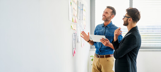 Panoramic picture of two colleagues planning business ideas at office