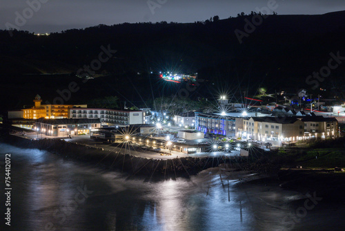 Night view from a hill side over looking a beach with buildings in the background