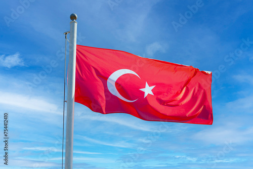 Turkish flag on a flagpole against the blue sky