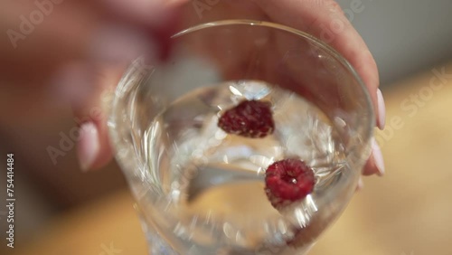 hand puts berries in a glass of water. Juice, summer drink