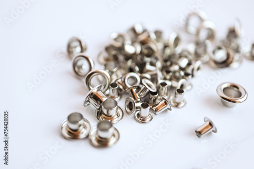 Metal silver eyelets on white table with bokeh blur in bright day light
